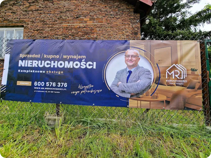 Baner reklamowy promujący nieruchomość, zawieszony na ogrodzeniu posesji, przedstawiający profesjonalną ofertę sprzedaży. Idealne rozwiązanie dla skutecznego marketingu nieruchomości.